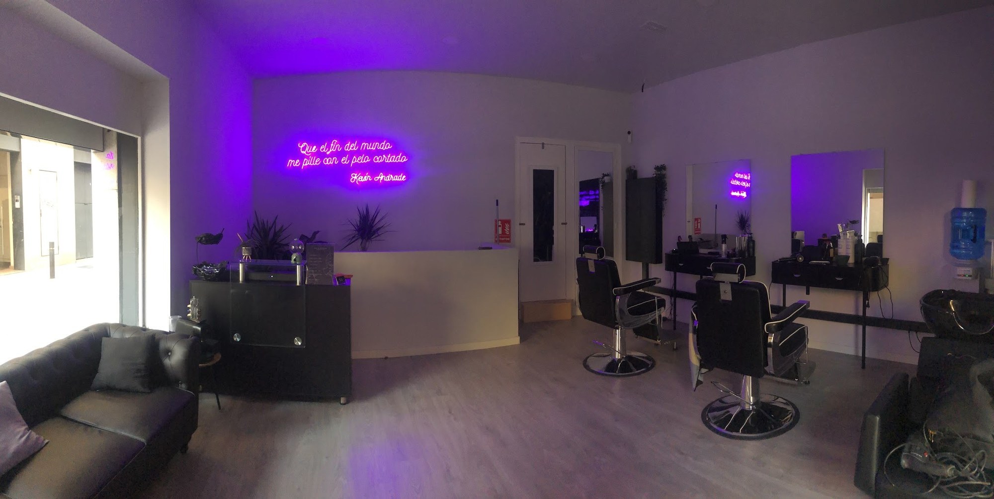 Interior de la barbería con la luz de neón morado encendida.