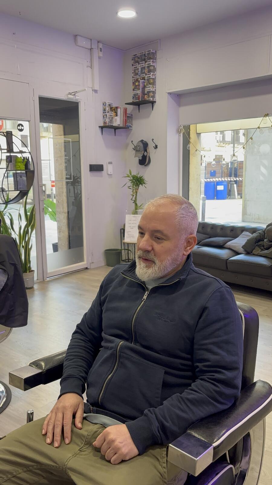 Cliente sentado en el sillón de la barbería antes de la prótesis capilar.