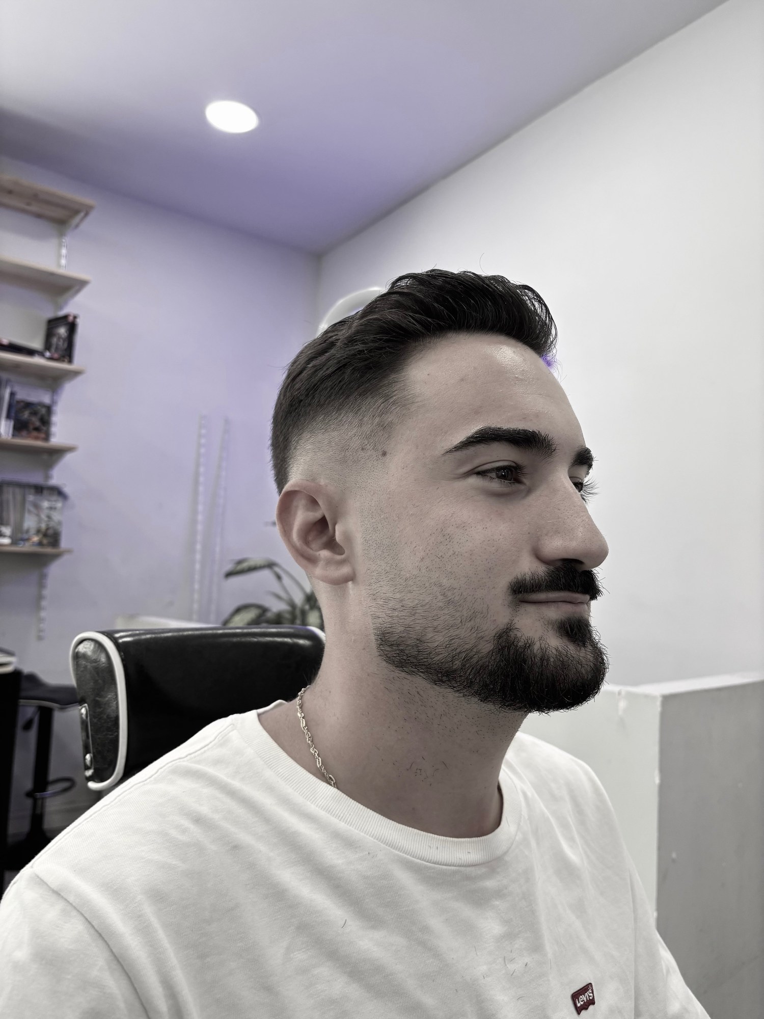 Retrato de perfil de un cliente con la barba recién perfilada en la barbería.